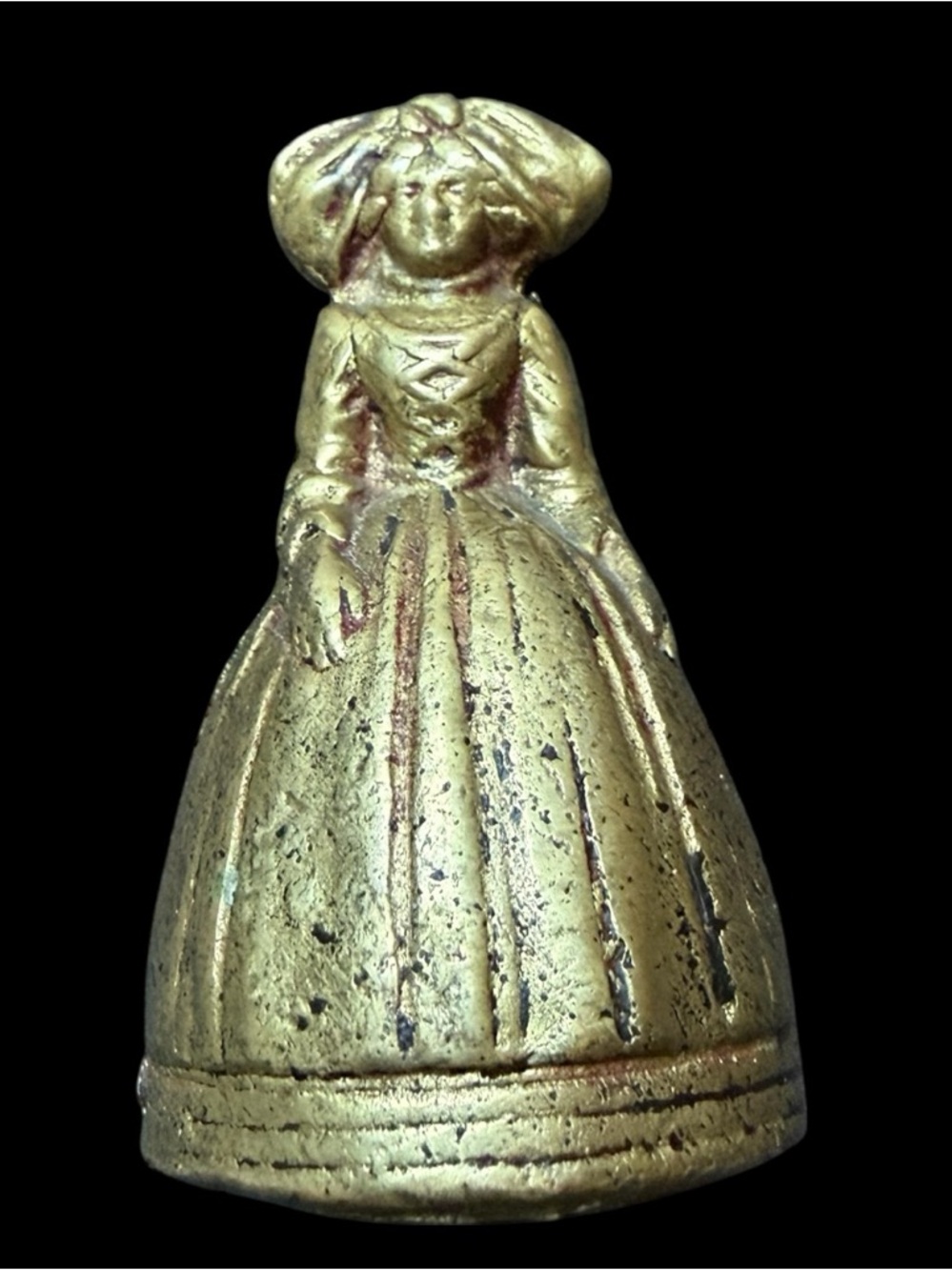 A vintage brass figural bell depicting a woman in a bell-shaped dress